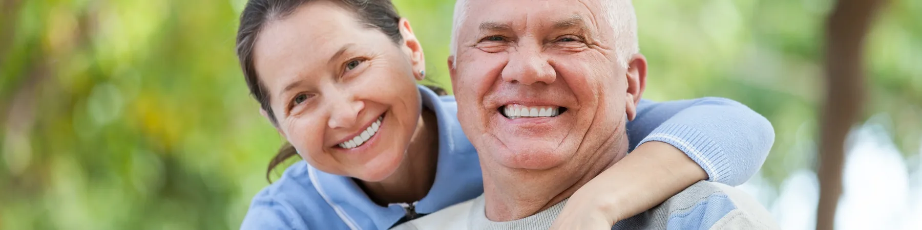 An older couple smiling together outdoors.